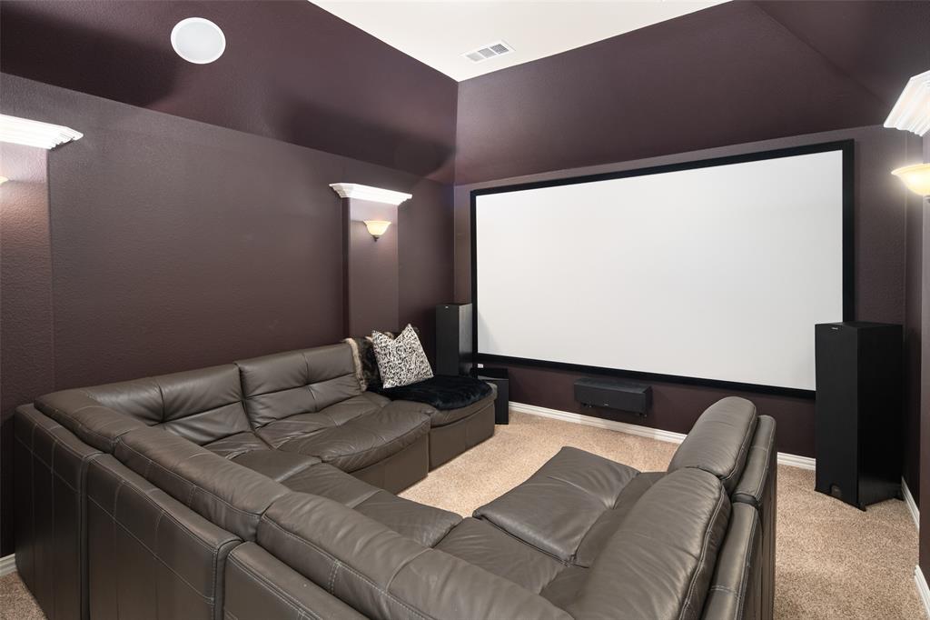 Media room featuring high vaulted ceilings, wall-mounted screen, integrated sconce lighting, and carpeting