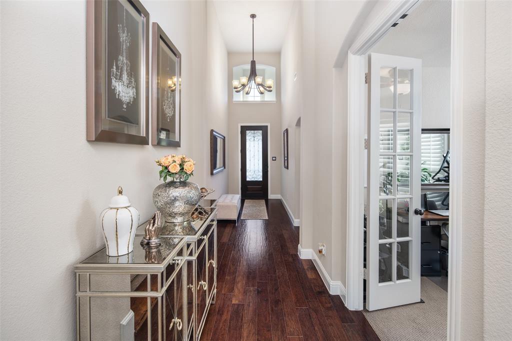 Entryway featuring high ceilings, wood-finish flooring, a multi-arm chandelier, an arched transom window, and French-style glass-paneled doors