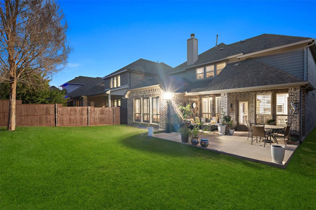 Brick and siding exterior featuring a concrete patio, wood fencing, and a manicured lawn