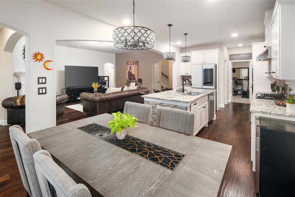 Kitchen featuring white shaker-style cabinetry, stone-finish countertops, stainless steel appliances, a center island with a dual-basin sink, and dark wood-finish flooring