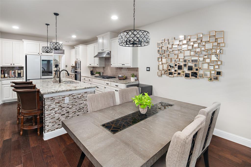 Kitchen featuring white cabinetry, stone countertops, a center island with stone tile detailing, recessed lighting, and metal pendant fixtures, all complemented by wood-finish flooring
