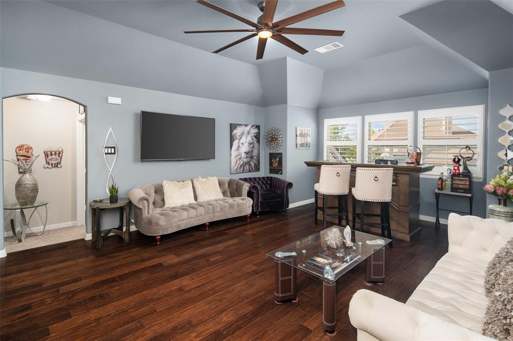 Vaulted ceilings, dark wood-finish flooring, multi-blade ceiling fan, arched doorway, and plantation shutters