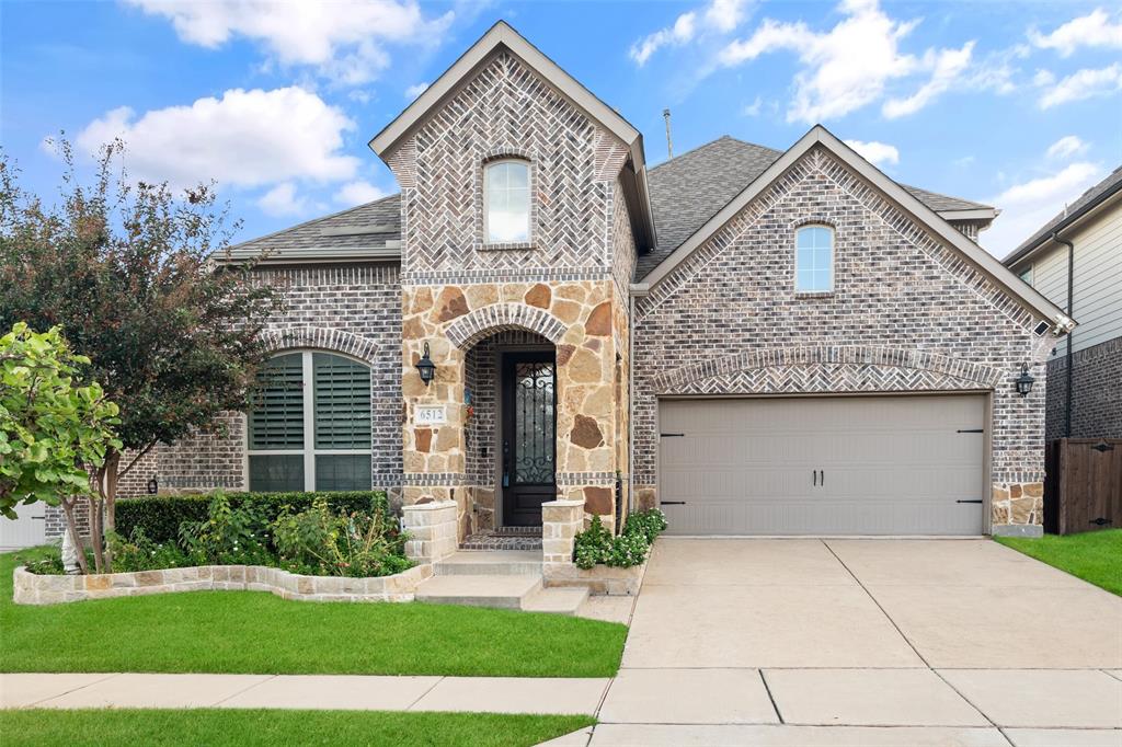 Multi-gabled brick exterior featuring decorative herringbone masonry, natural stone accents, arched entryway, and attached garage