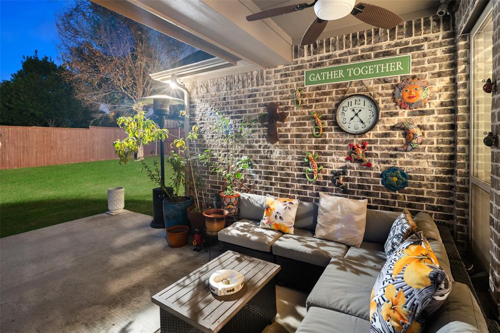 Covered patio featuring a brick accent wall, concrete flooring, and an integrated ceiling fan
