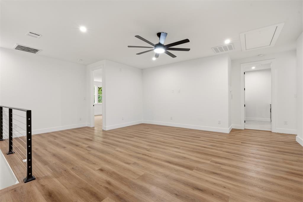 Open-concept interior featuring wood-finish flooring, recessed lighting, a modern ceiling fan with integrated lighting, and a cable-style staircase railing