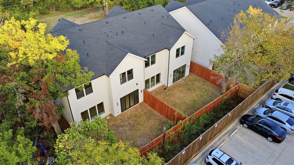 Two-story structure featuring light-colored exterior finish, a pitched asphalt shingle roof, multi-pane windows, and a wood-slat privacy fence enclosing the grounds