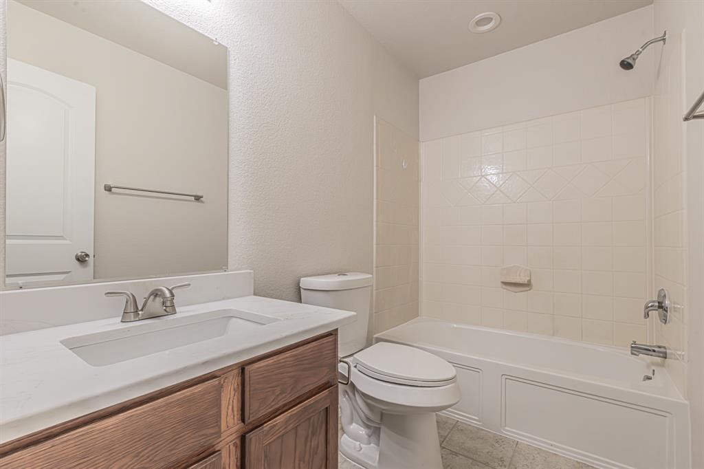 Full bathroom featuring a wood-finish vanity with an integrated sink, polished chrome faucet, and a large wall-mounted mirror