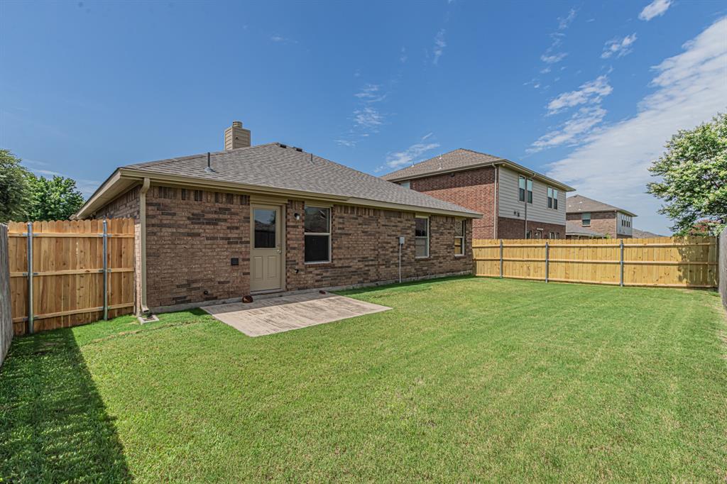 Expansive green lawn with a durable wood privacy fence, a concrete patio, and a brick exterior