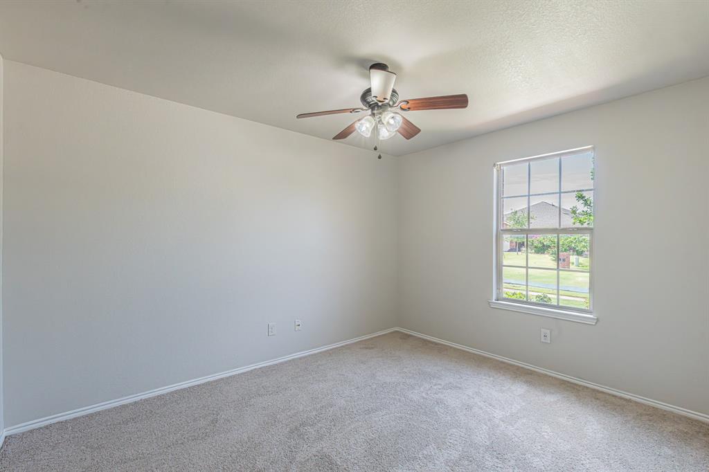 Neutral tone walls featuring a single window and a ceiling fan with light fixture
