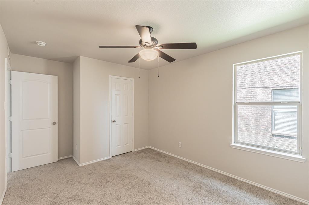 Carpeted room featuring a ceiling fan with integrated lighting, a large window, and two paneled doors