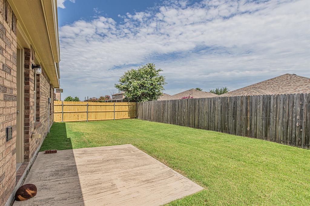 Expansive backyard featuring a concrete patio, verdant lawn, and privacy fencing