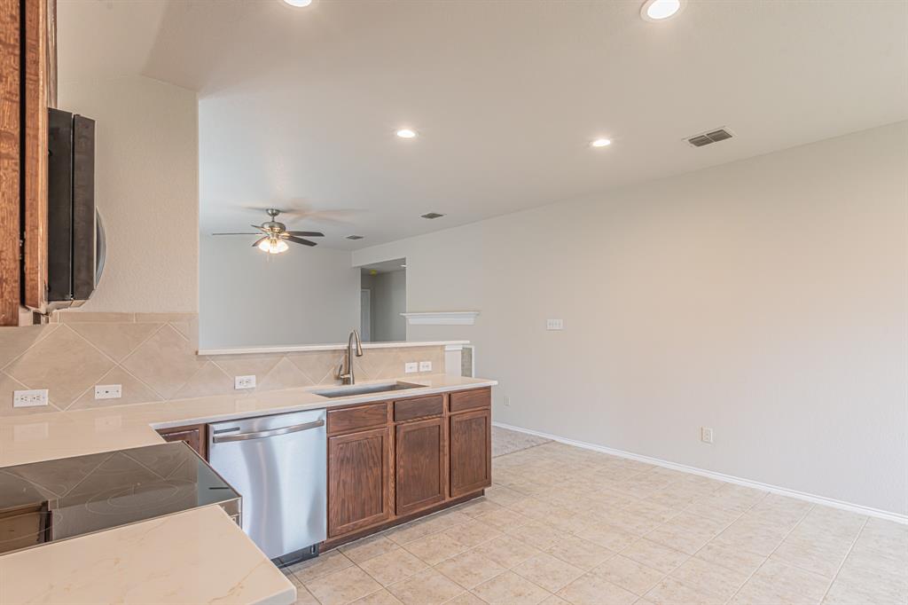 Kitchen with wood-finish cabinetry, stainless steel dishwasher, and a built-in cooktop