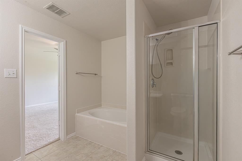 Bathroom featuring a combination shower and tub, glass-enclosed shower, built-in bathtub, tile flooring, and light-toned walls