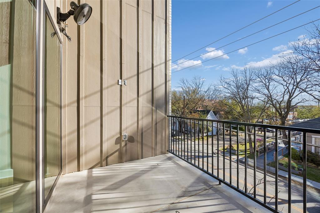 Covered balcony featuring vertical board siding, concrete flooring, and a black metal railing