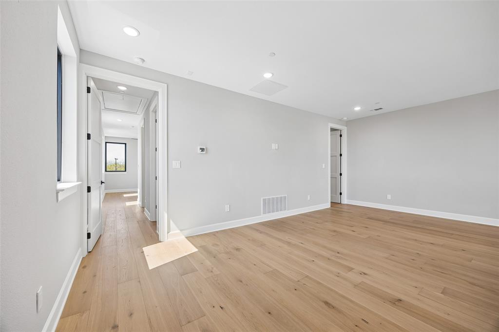 Neutral-toned interior space featuring wood-finish flooring, recessed lighting, and white shaker-style interior doors