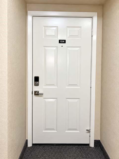 White six-panel door featuring a brushed nickel lever handle, integrated electronic keypad, and door-mounted peephole White six-panel door featuring a brushed nickel lever handle, integrated electronic keypad, and door-mounted peephole
