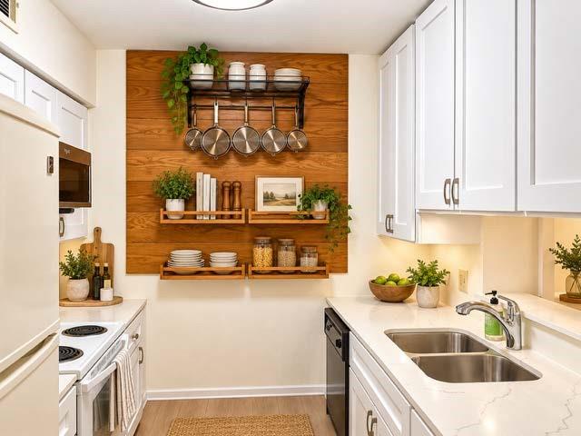 Staged Kitchen featuring white shaker-style cabinetry, quartz countertops, dual-basin stainless steel sink, wood-finish wall paneling, and mounted wooden shelving