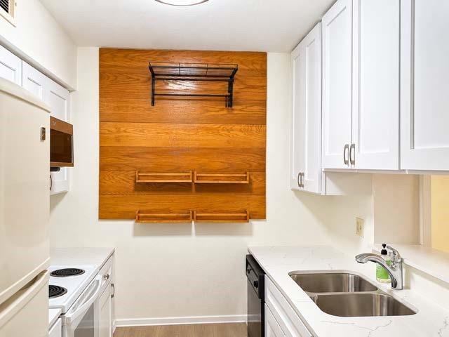 Kitchen featuring white shaker-style cabinetry, quartz countertops, a double-basin stainless steel sink with a chrome faucet, and a decorative wood-finish wall accent with integrated shelving