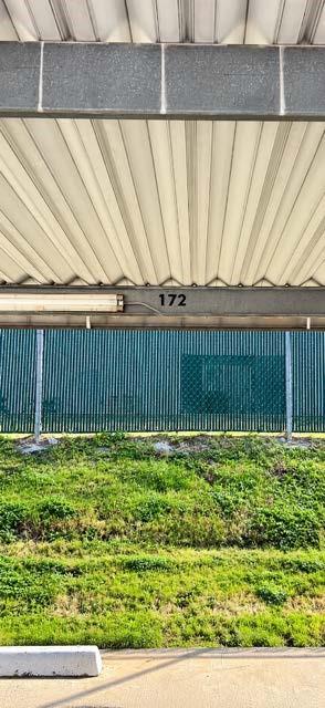 Covered parking #172  space featuring a corrugated metal roof, integrated overhead lighting, and numbered stall identification