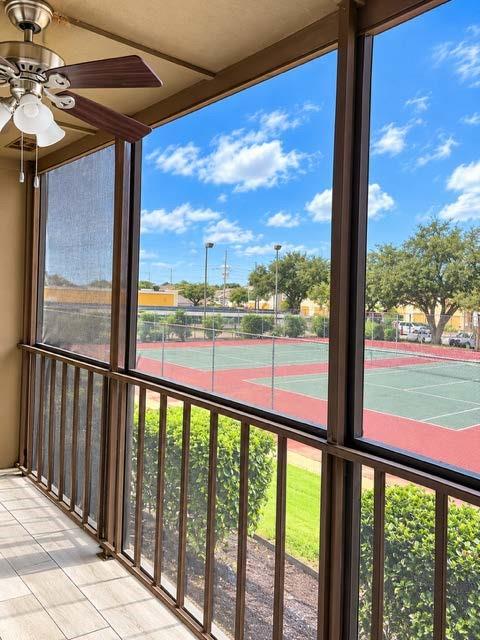Screened-in porch featuring tiled flooring, a ceiling-mounted light fixture with fan, and metal railings