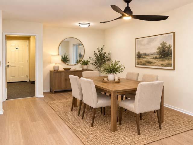 Stages Neutral-toned interior space featuring light wood-finish flooring, a contemporary three-blade matte black ceiling fan with integrated lighting, and a flush-mount circular ceiling fixture