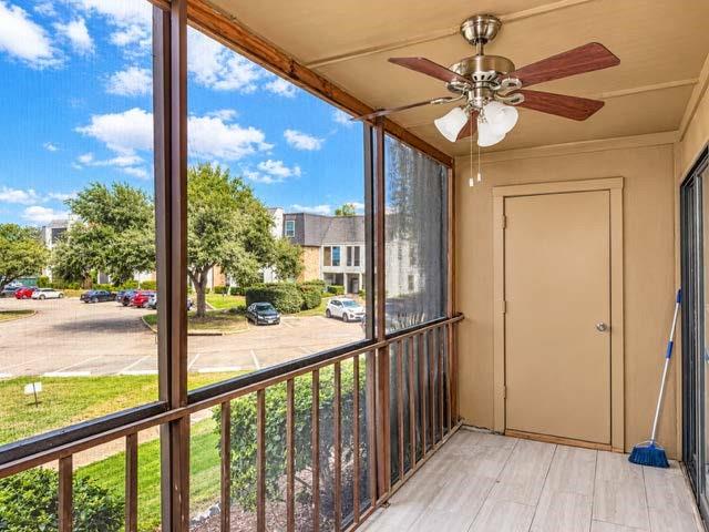 Screened-in balcony featuring wood-finish flooring, metal railing, integrated storage closet, and ceiling fan with light fixture
