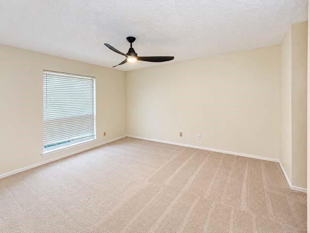 Neutral wall coloring, wall-to-wall carpeting, window with fitted horizontal blinds, and a three-blade matte black ceiling fan with an integrated light fixture