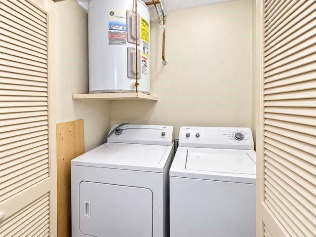 Laundry area featuring dual louvered closet doors and a wall-mounted shelving unit with an electric water heater