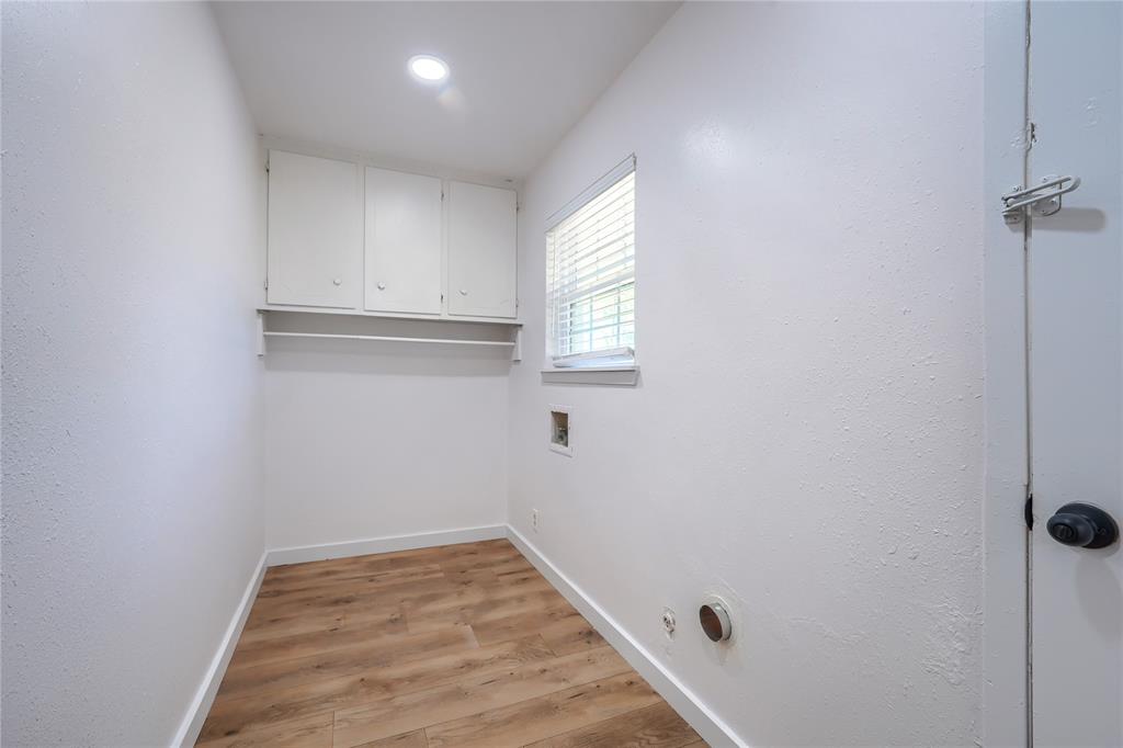 Utility space featuring wood-finish flooring, white upper wall-mounted cabinetry, a recessed lighting fixture, and a window with horizontal blinds
