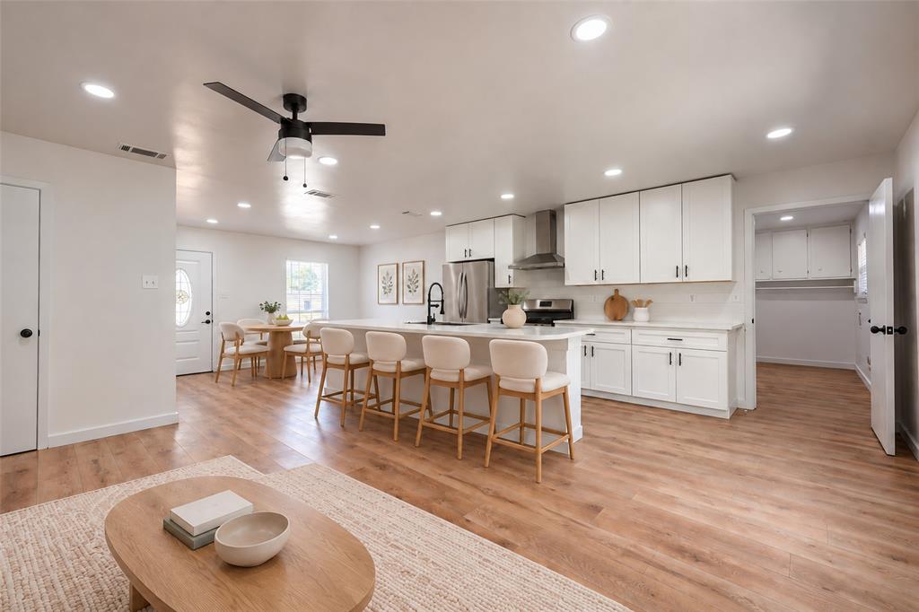 Kitchen featuring white cabinetry, an expansive island with a countertop, stainless steel appliances, recessed lighting, and wood-finish flooring