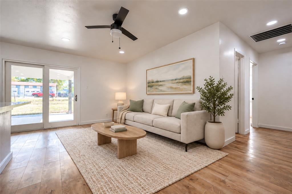 Interior space featuring wood-finish flooring, recessed lighting, matte black ceiling fan, and glass sliding door access to exterior grounds