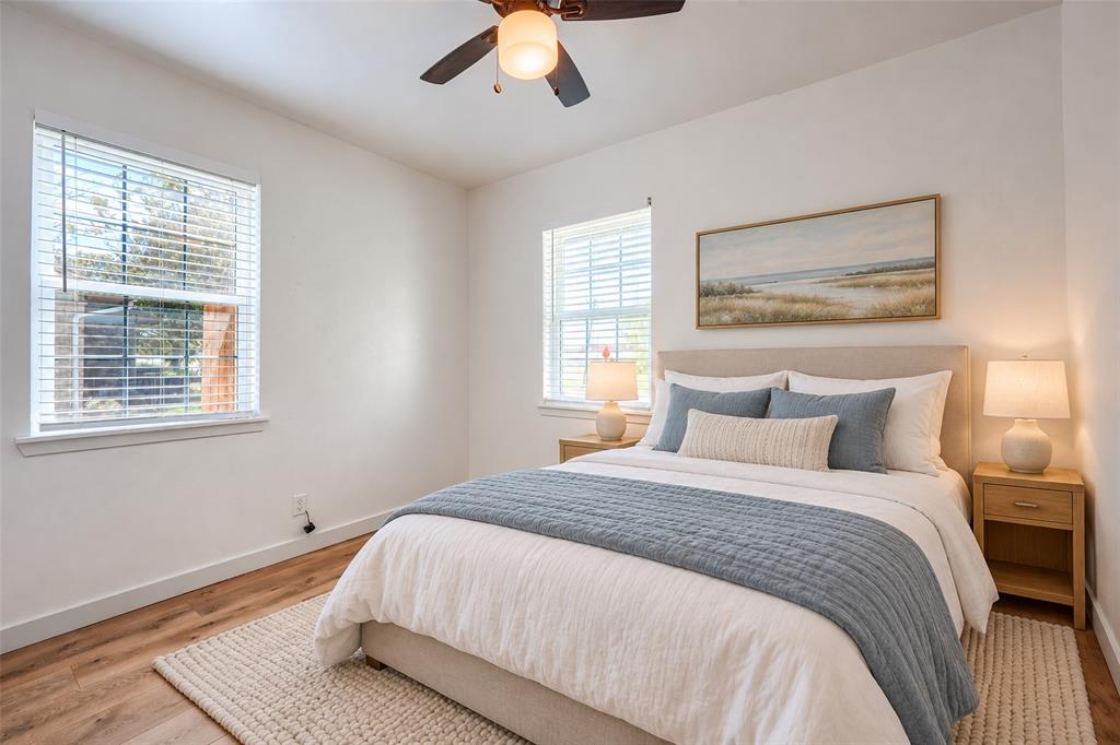 Wood-finish flooring, dual windows with horizontal blinds, and a ceiling-mounted light fixture with a fan