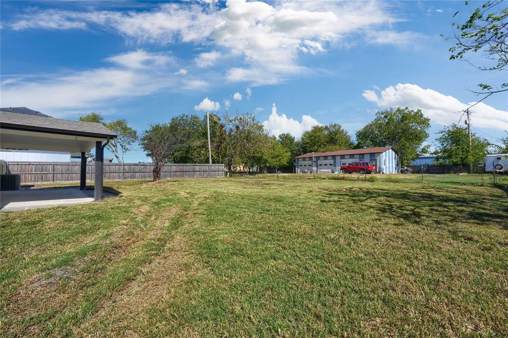 Expansive backyard featuring a concrete patio, wood privacy fencing, and mature trees
