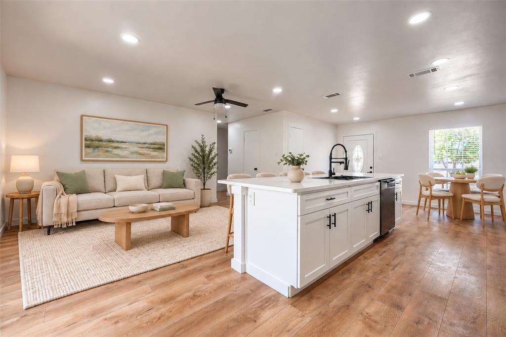 Open-concept interior featuring wood-finish flooring, recessed lighting, and a central island with a contrasting faucet