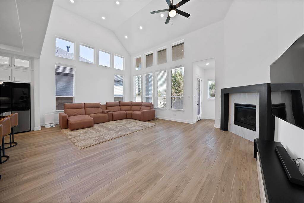 Vaulted ceilings, expansive windows, wood-finish flooring, recessed lighting, and a fireplace with a black mantle