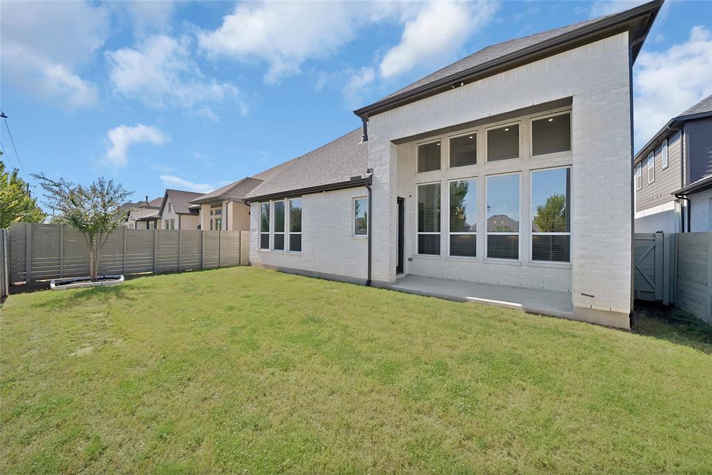 White brick exterior featuring expansive floor-to-ceiling windows, a concrete patio, and a fenced backyard
