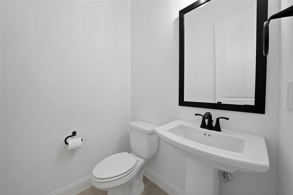 Pedestal sink featuring a matte black widespread faucet, rectangular mirror with a black frame, and matching matte black hardware