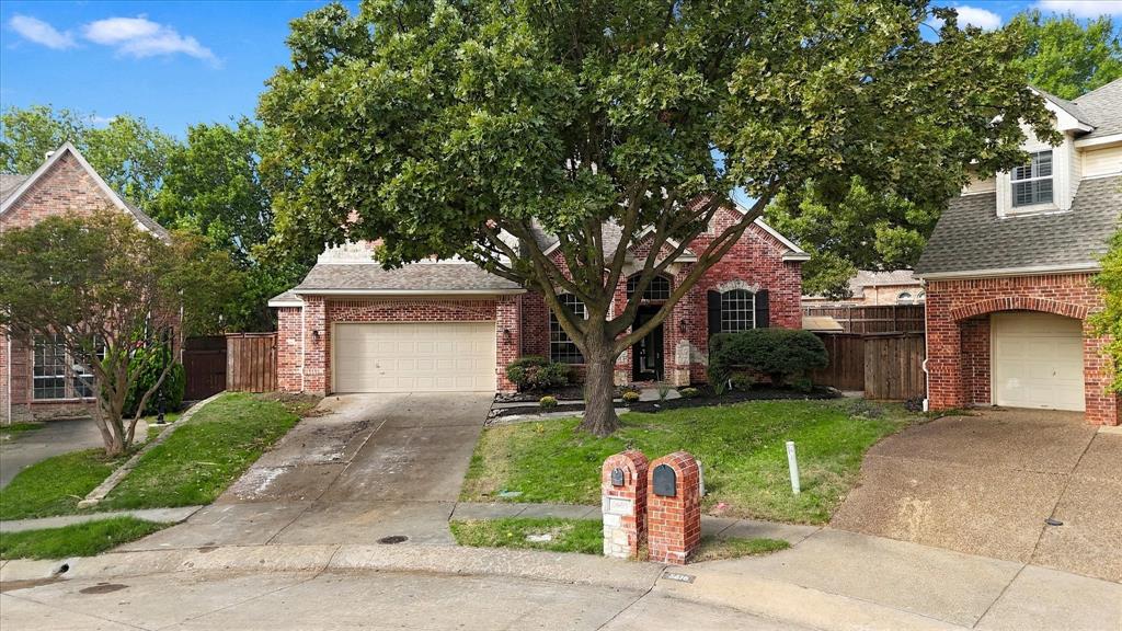 Traditional brick exterior featuring arched entryways, multi-car garage space, and mature landscaping