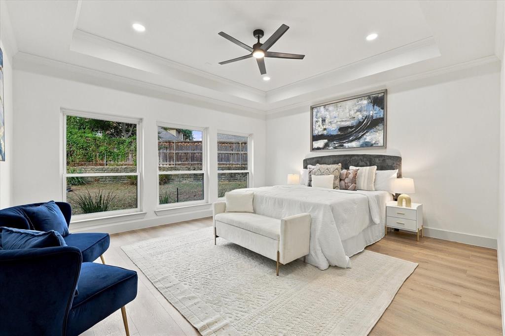 Tray ceiling with recessed lighting, wood-finish flooring, and expansive windows