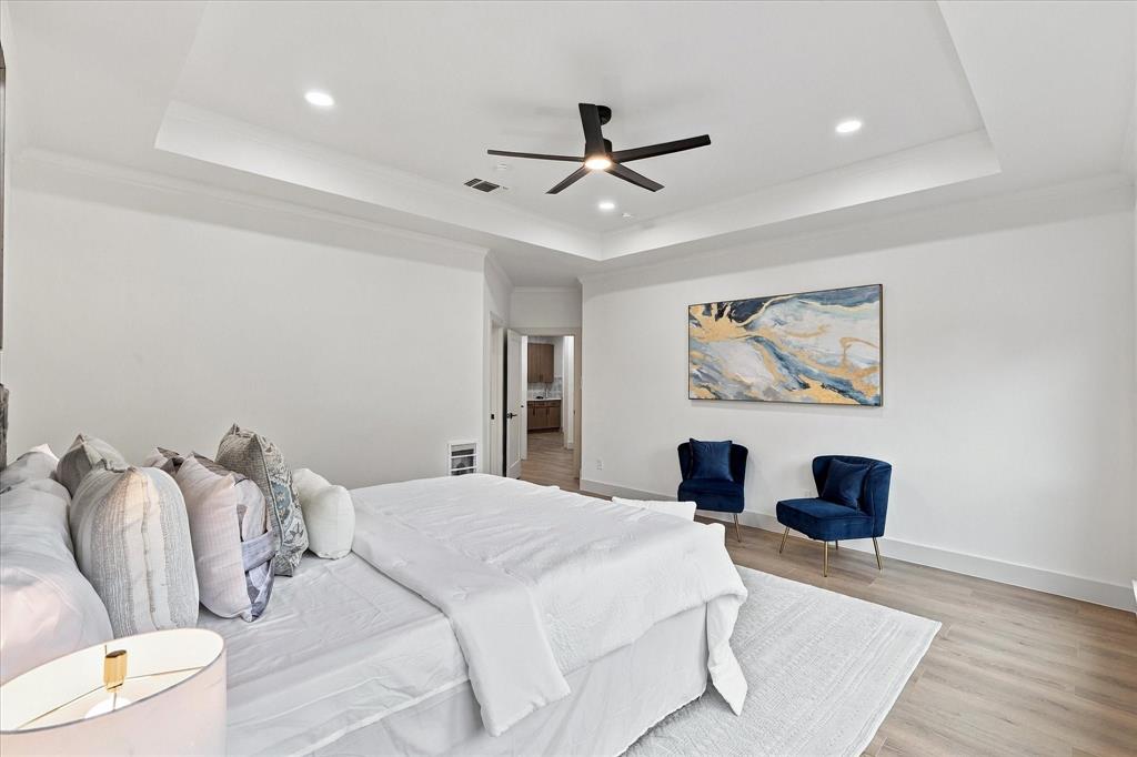 Tray ceiling featuring recessed lighting and a central matte black ceiling fan, complemented by wood-finish flooring