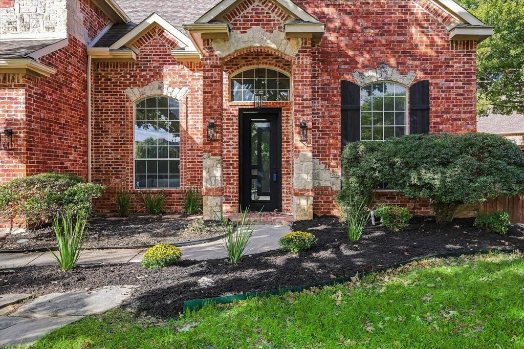 Brick exterior featuring arched windows, stone masonry accents, black decorative shutters, and a covered entryway Brick exterior featuring arched windows, stone masonry accents, black decorative shutters, and a covered entryway