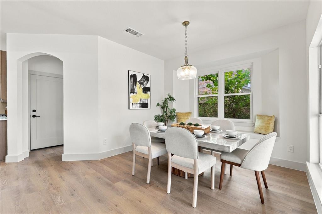 Dining area featuring wood-finish flooring, a built-in window seat, an arched doorway, and a pendant light fixture