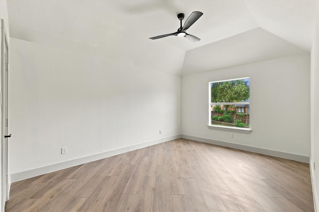Vaulted ceiling featuring a matte black three-blade ceiling fan and wood-finish flooring