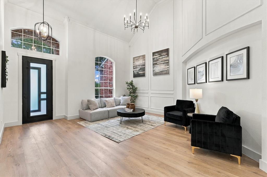 Entryway featuring vaulted ceilings, wood-finish flooring, wainscoting detail, arched windows, and a black-framed glass front door