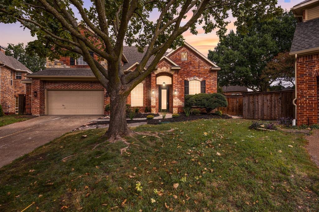Traditional brick exterior featuring an arched entryway, gabled rooflines, attached two-car garage, and mature tree landscaping Traditional brick exterior featuring an arched entryway, gabled rooflines, attached two-car garage, and mature tree landscaping