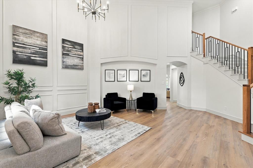 Two-story foyer featuring paneled walls, wood-finish flooring, a tiered chandelier, and a staircase with metal balusters and wood handrails