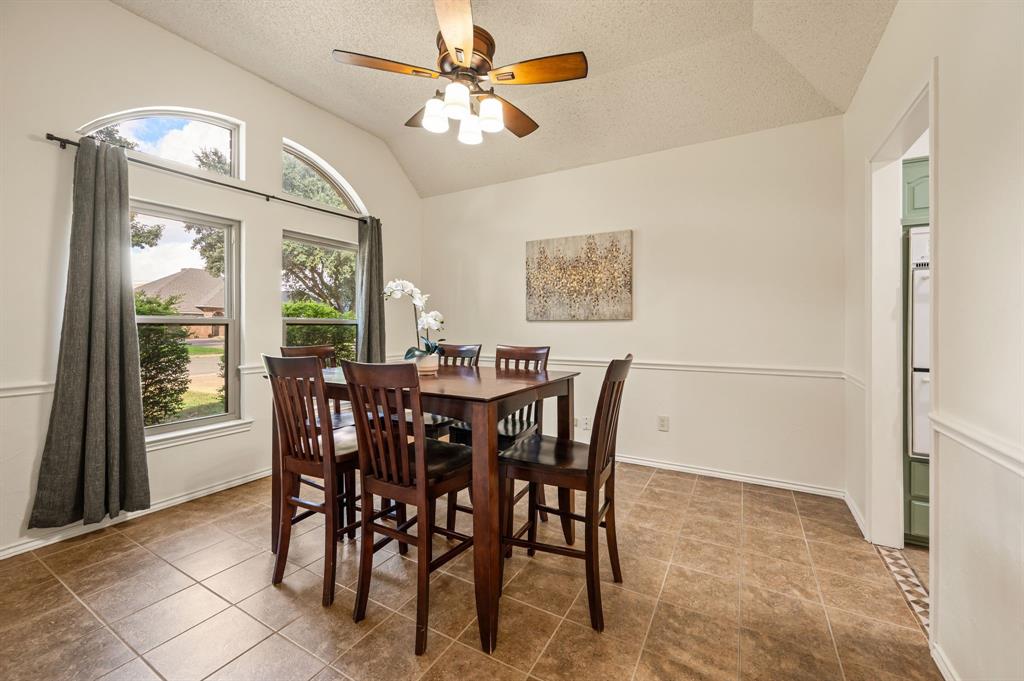 Dining space featuring high vaulted ceilings, tiled flooring, chair rail molding, and arched windows