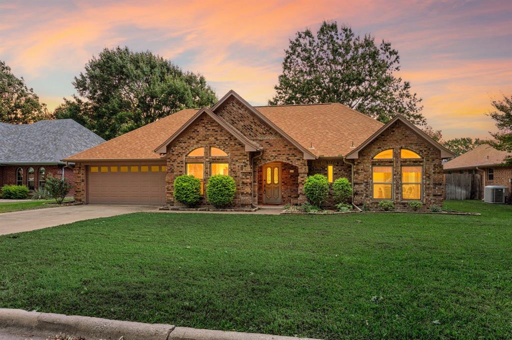 Brick exterior featuring a multi-gabled roofline, arched windows, covered entryway, and attached multi-car garage