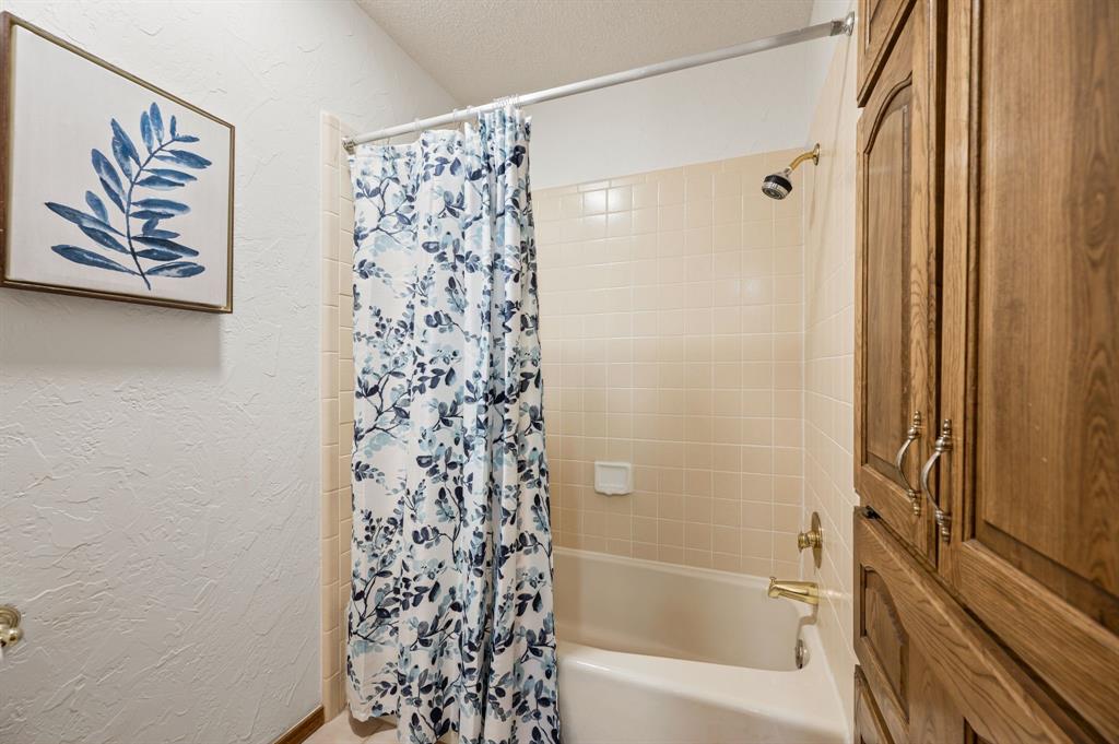 Full-height built-in wood cabinetry, tub with tile surround, and brass-finish plumbing fixtures
