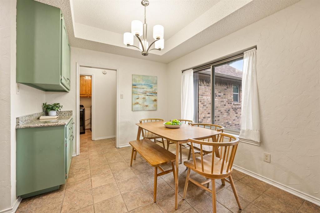 Dining space featuring tile flooring, built-in cabinetry with stone-finish countertops, a multi-arm chandelier, and a sliding glass door